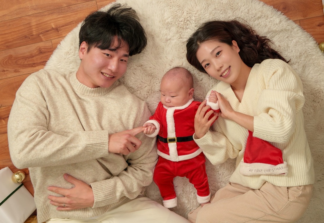 Parents and their baby sharing a Christmas family portrait